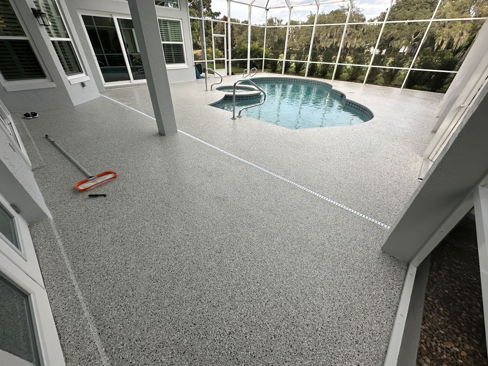 Gray flake pool deck coating on a screened lanai with pool and spa